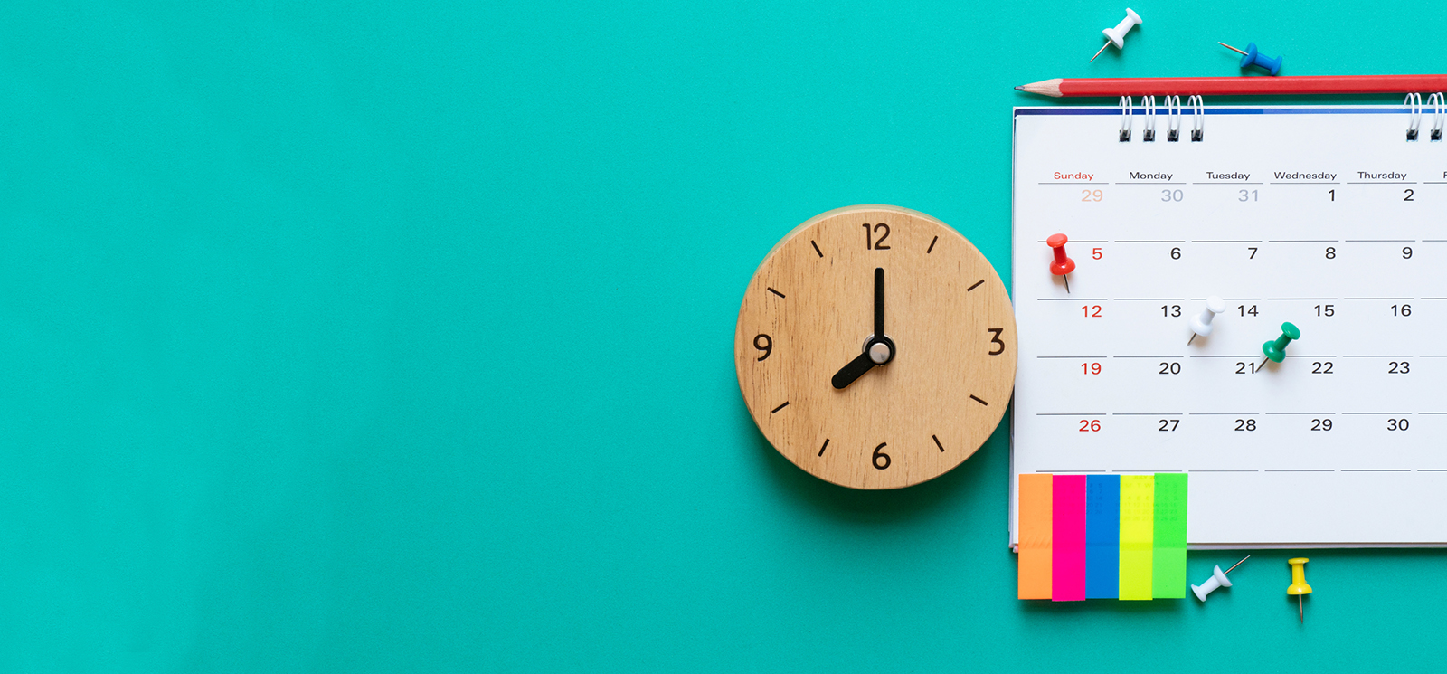 Foto von einer Wanduhr und einem Wandkalender auf türkisfarbenenm Untergrund